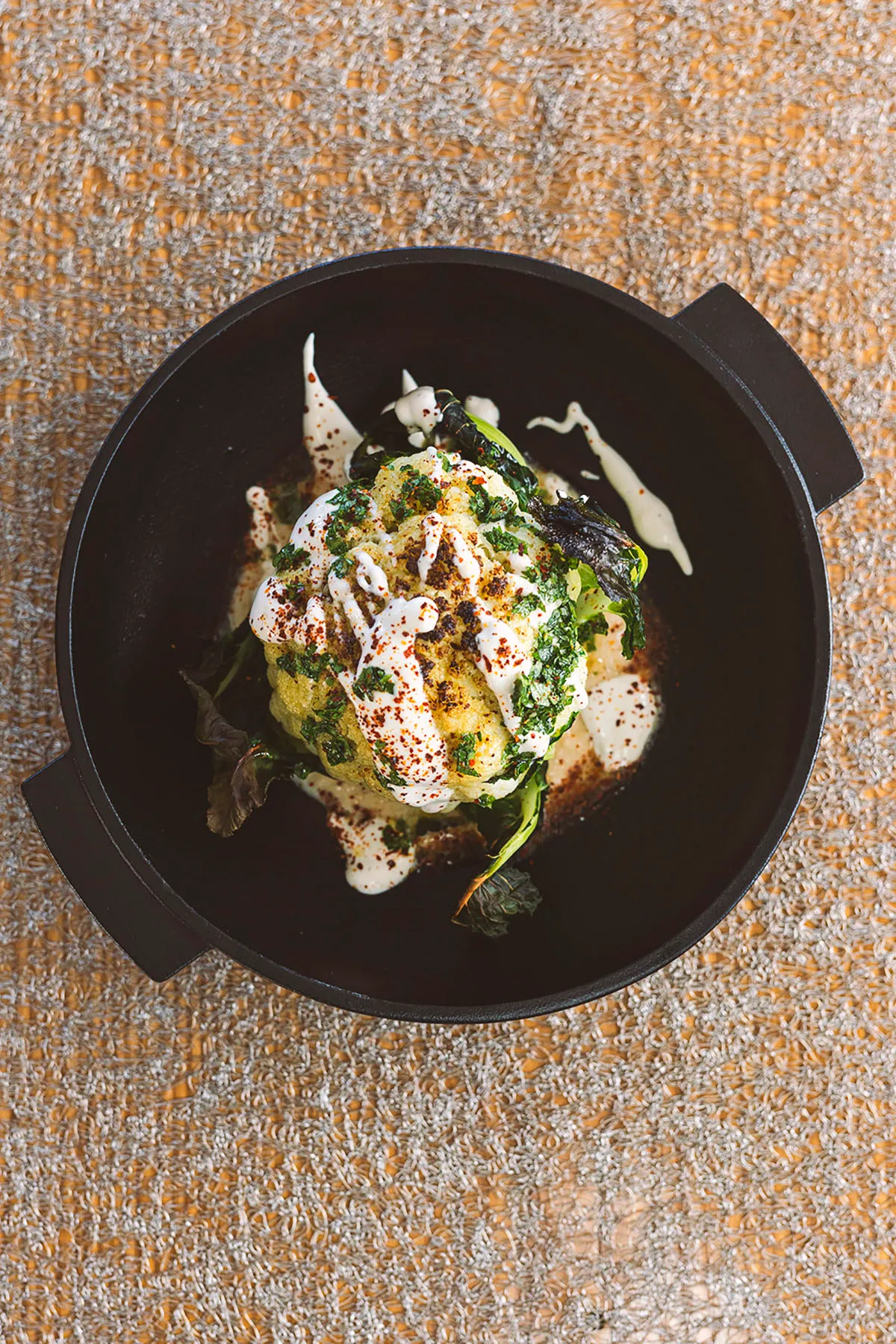 Burrata with greens and sauce in a black pot