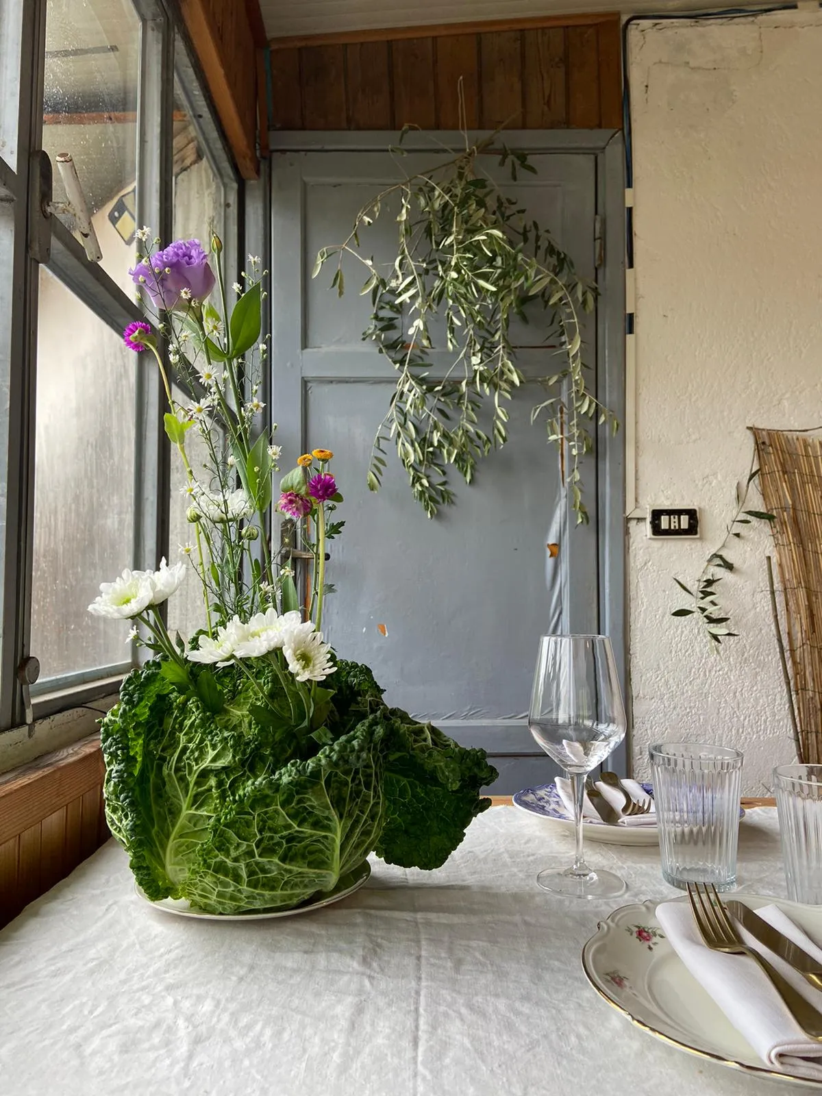 Savoy cabbage and flower centrepiece on a dining table by a window