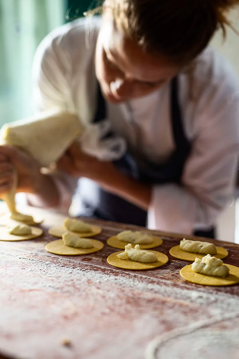Chef piping filling onto pasta rounds