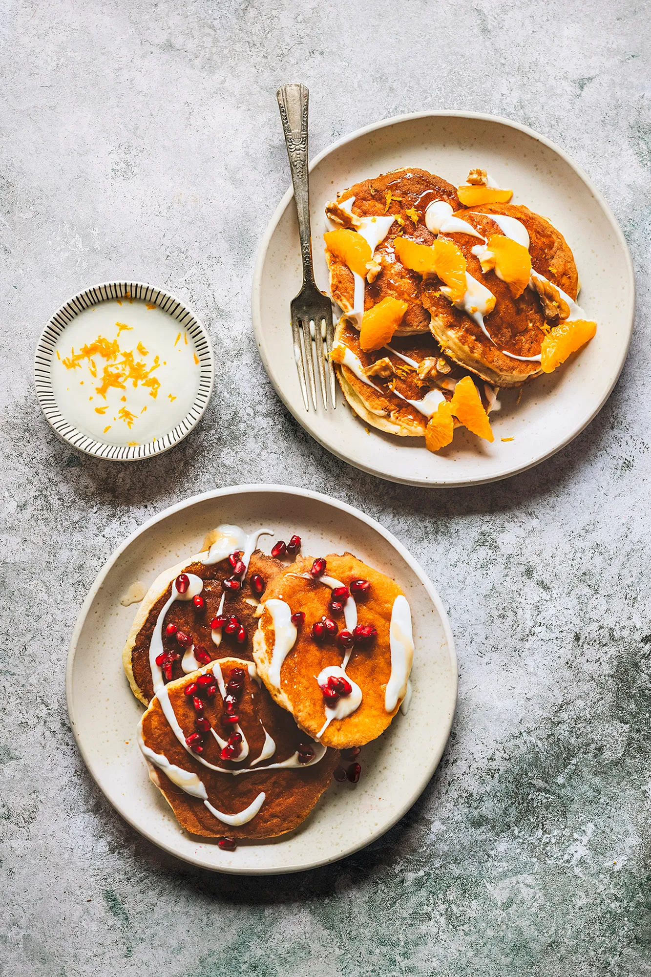 Pancakes with orange segments, yogurt and pomegranate seeds