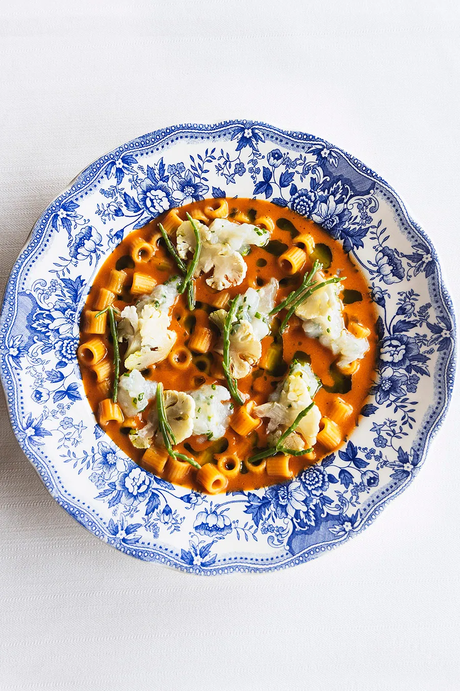 Pasta in tomato broth with cauliflower on a blue floral plate