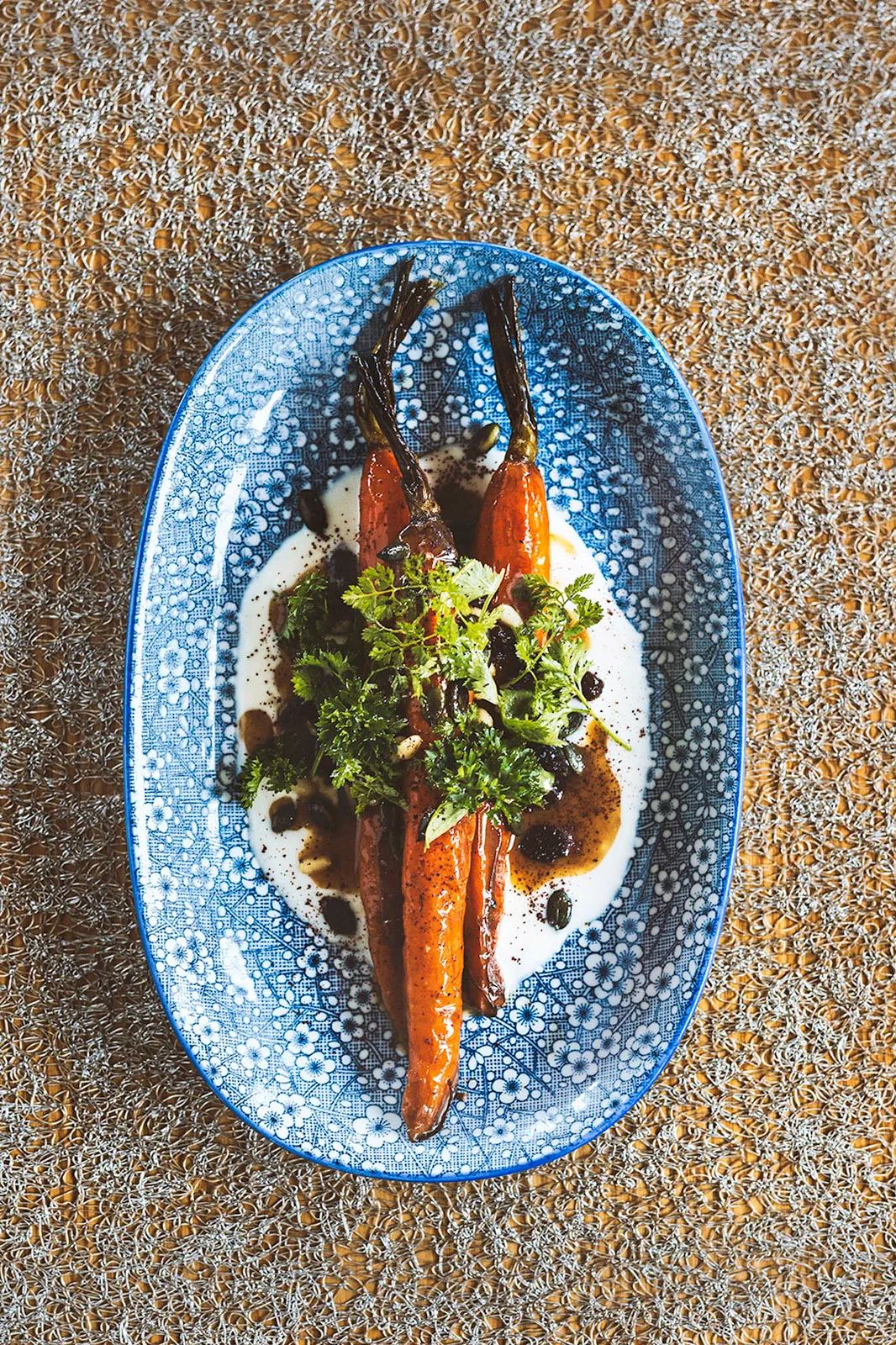 Roasted carrots with herbs and yogurt on a blue floral platter