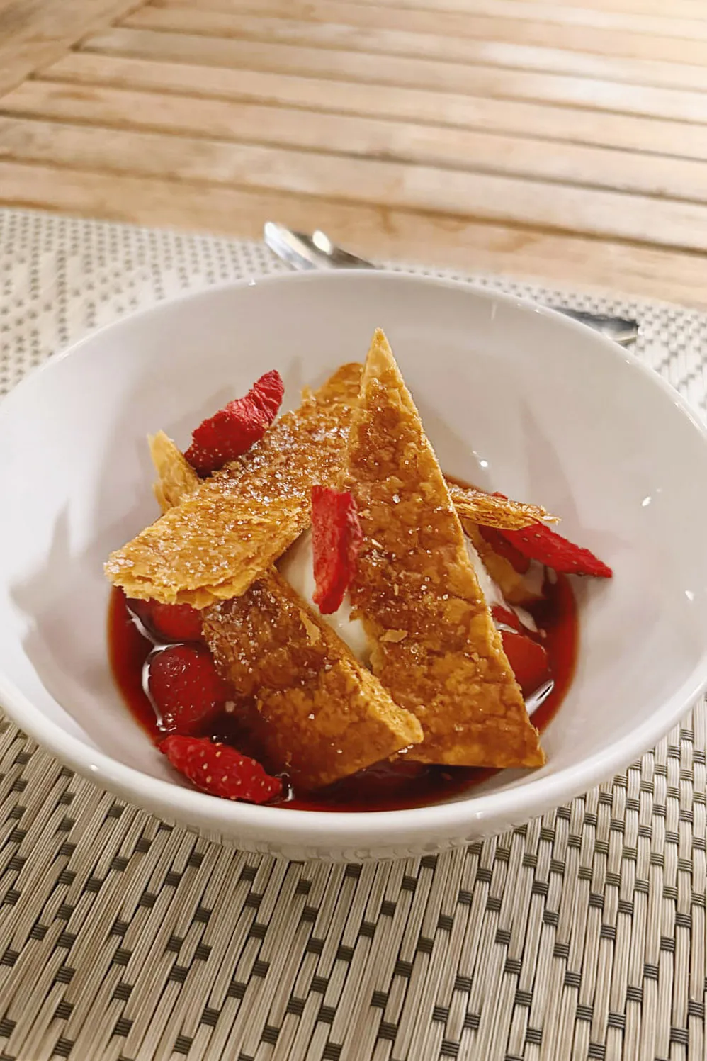 Dessert with strawberries and caramelised pastry in a white bowl
